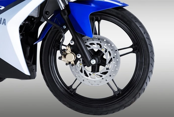 Ben nâng tháo bánh trước PKL M-Biker: chọn mã và thao tác 12 Hai tay thợ đang đỡ cụm bánh xe và từ từ rút trục ra khỏi càng phuộc theo phương thẳng song song mặt đất